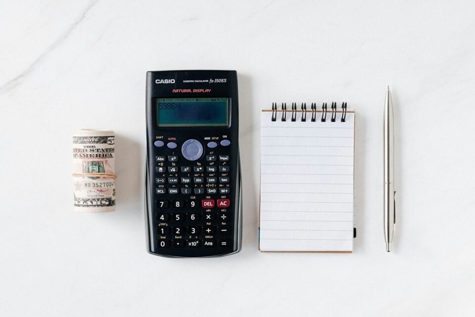 rolled up paper money calculator notebook and pen