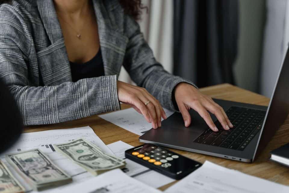 woman in plaid blazer reviewing finances on laptop